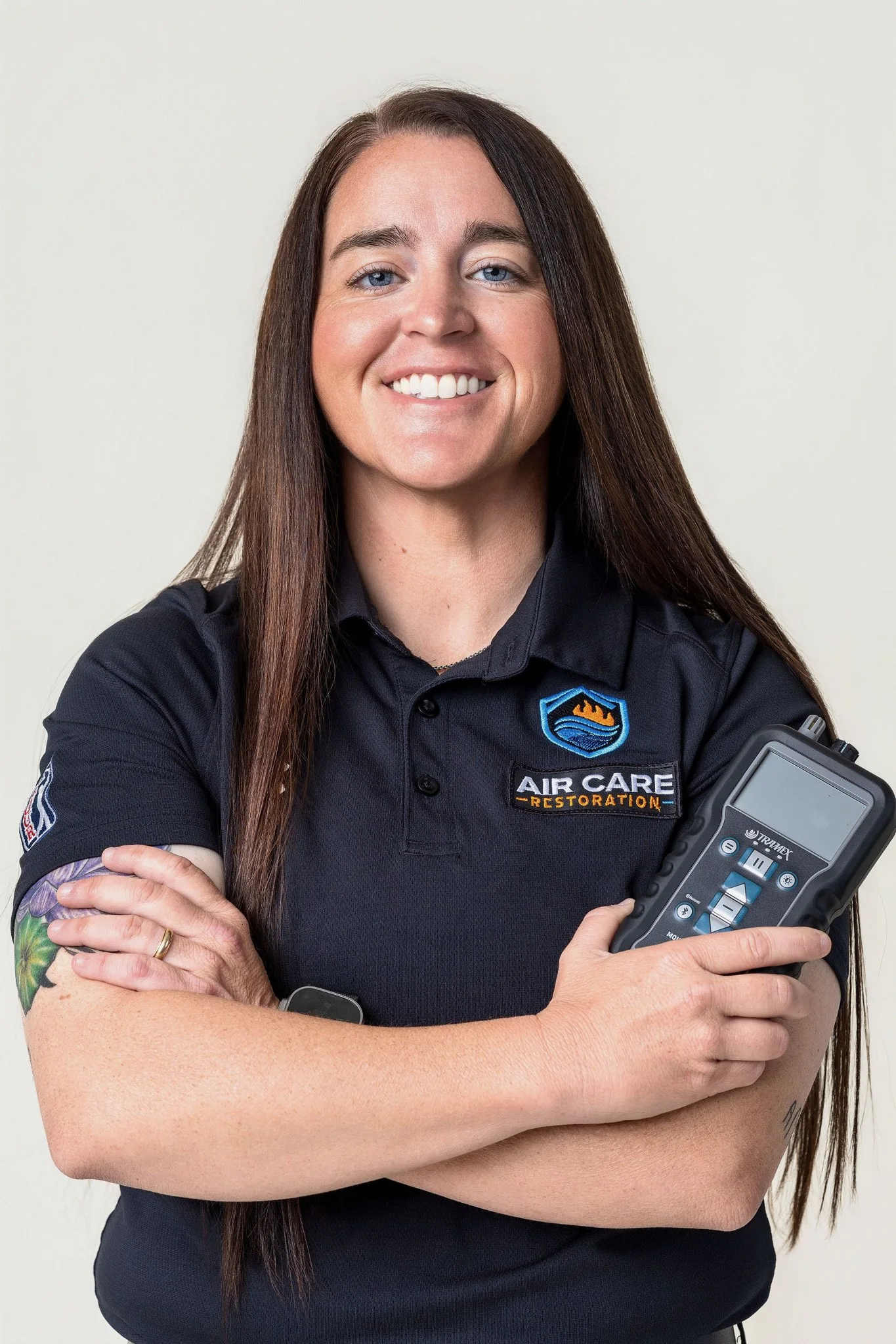 Female technician in Air Care Restoration polo holding moisture meter, Air Care Restoration